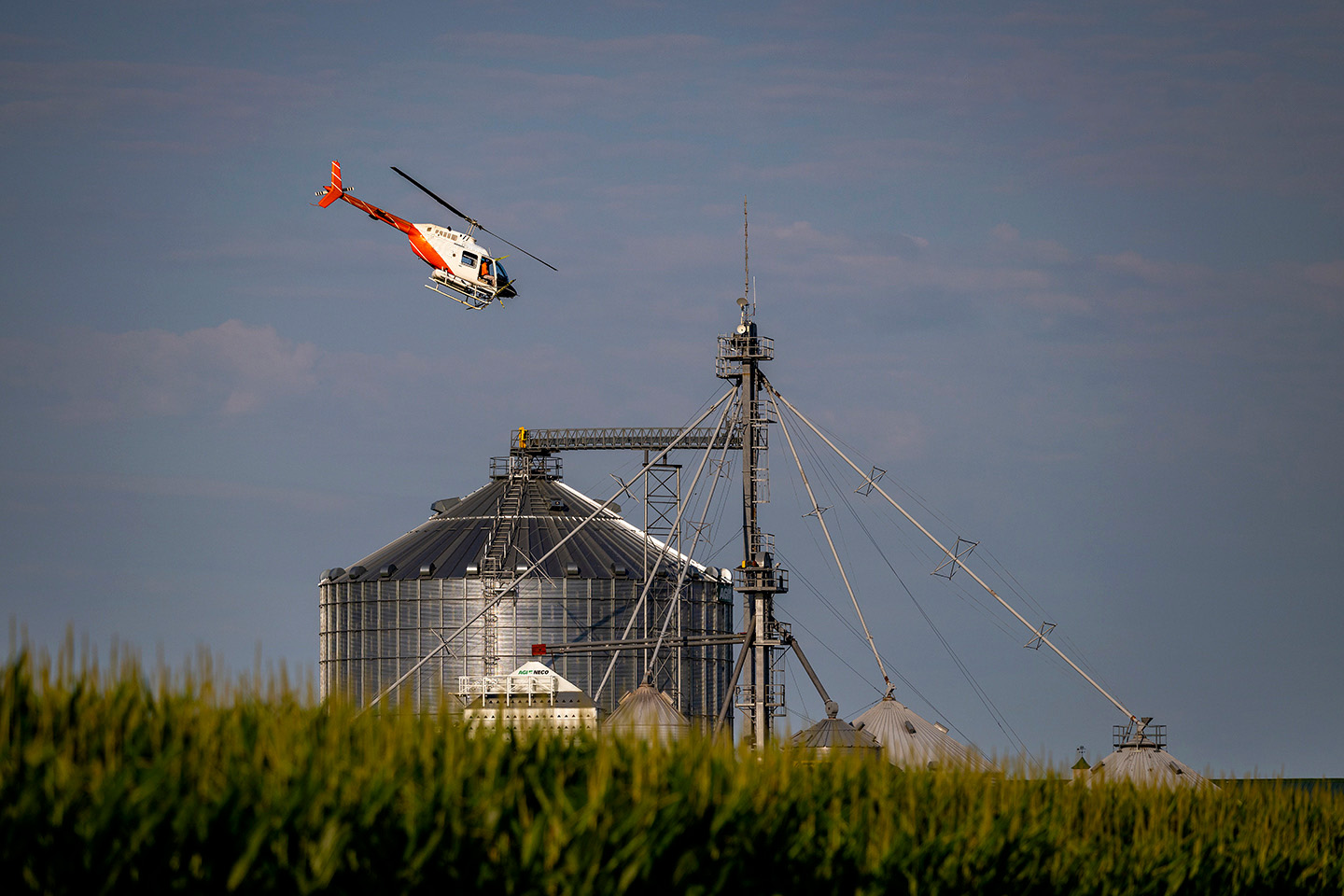 A spray helicopter flying above the grain silos