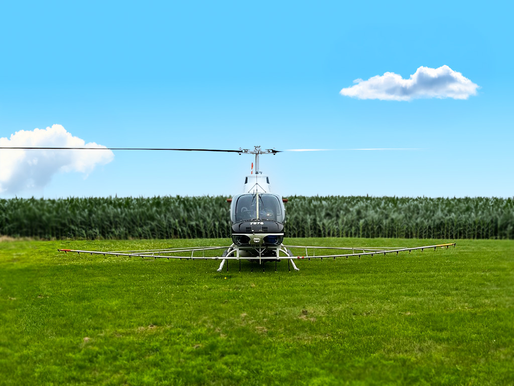 Photo of a spray helicopter with cornfields behind it.